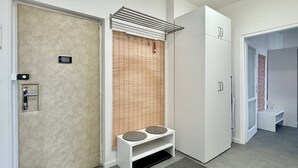 Moderni hotellihuone, jossa on ovi, kahdella tyynyllä varustettu penkki, patteri ja vaatekaappi.