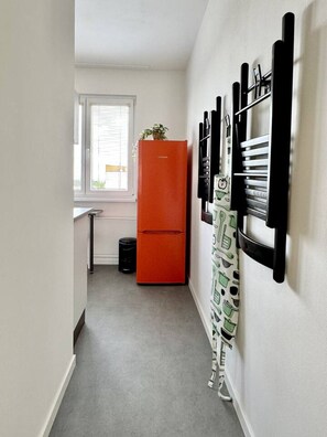 A narrow hallway with a red refrigerator, a window with blinds, and a wall-mounted knife rack.