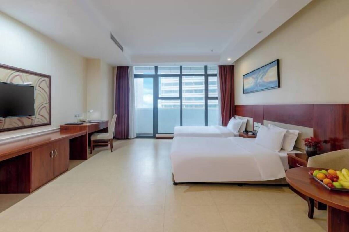 Ein Hotelzimmer mit Bett, Schreibtisch, Fernseher und einem großen Fenster.