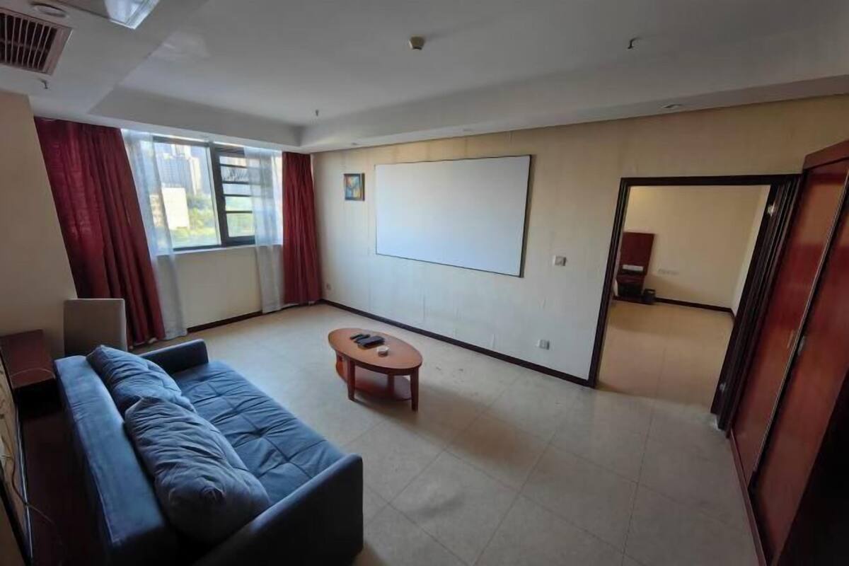 Ein Zimmer mit einer Couch, einem kleinen Tisch, einer Whiteboard-Tafel und einer Tür.