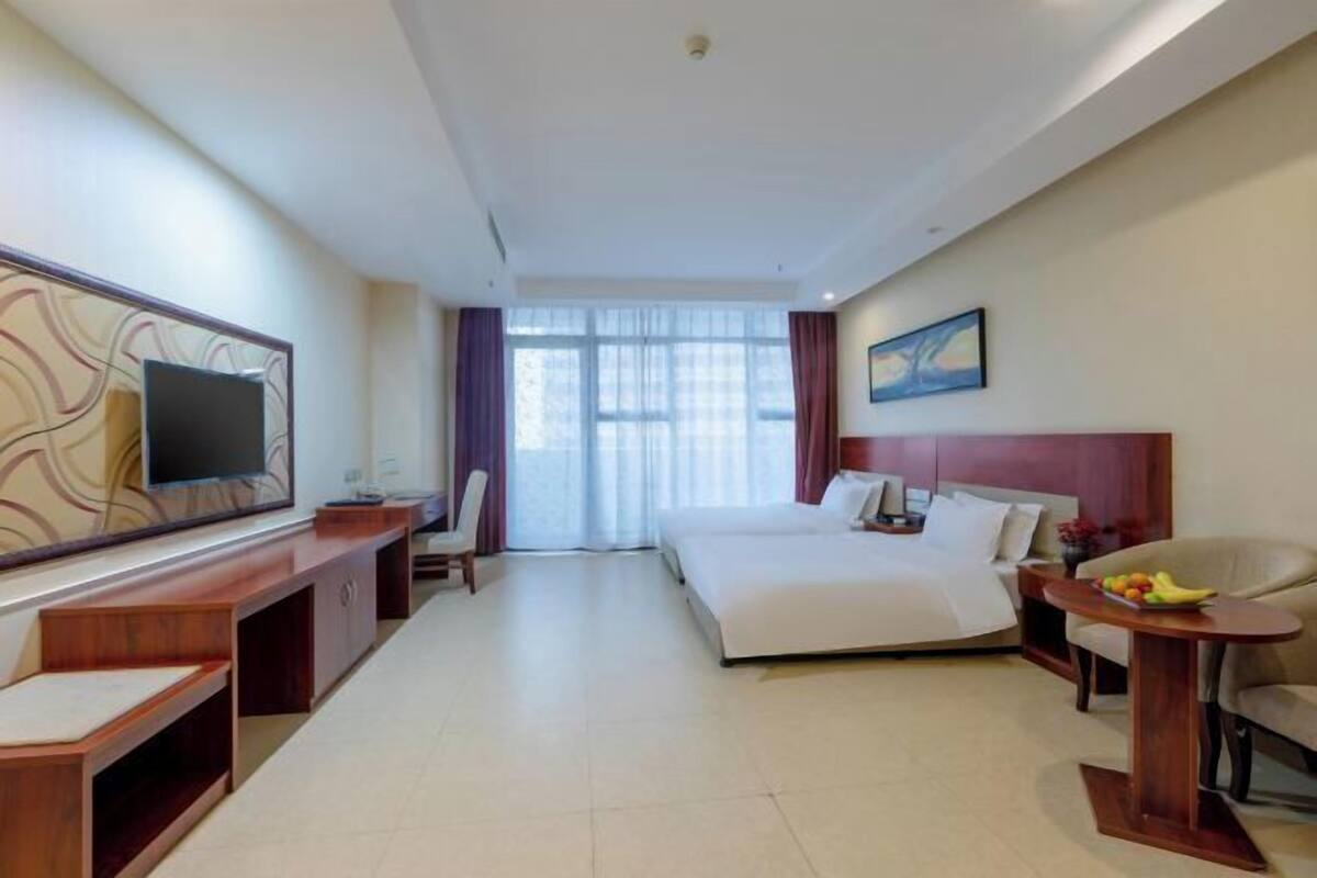 Ein Hotelzimmer mit Bett, Fernseher, Schreibtisch und Stuhl.