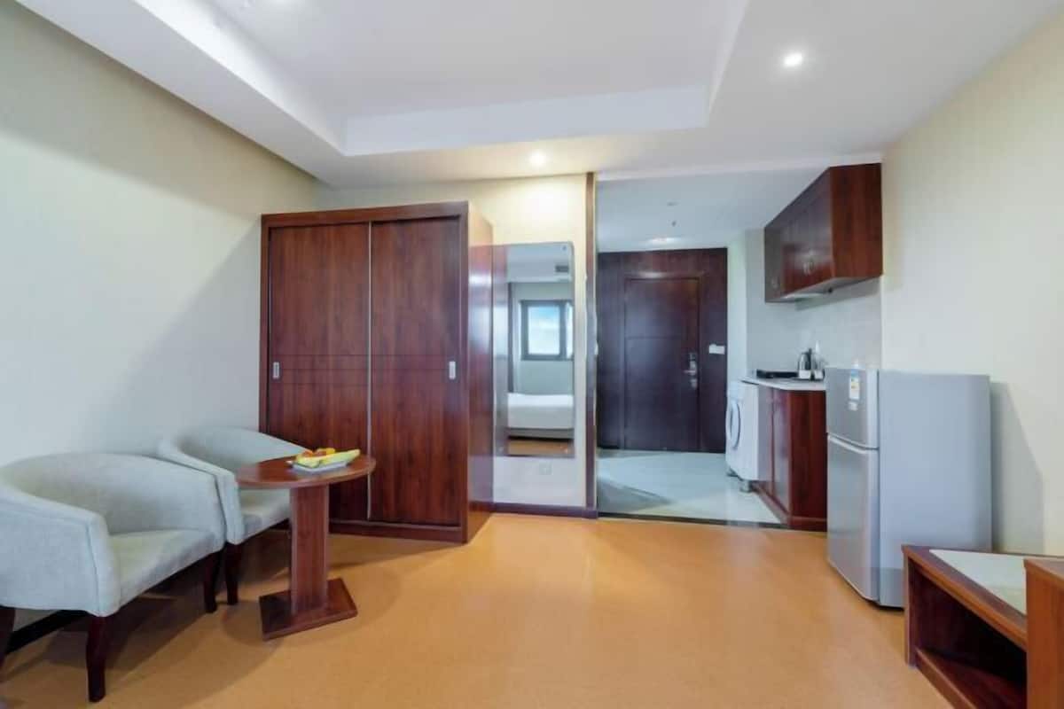 Ein kompaktes Hotelzimmer mit Küchenzeile, einer Sitzecke, einem kleinen Tisch mit Obst und einem Kleiderschrank.