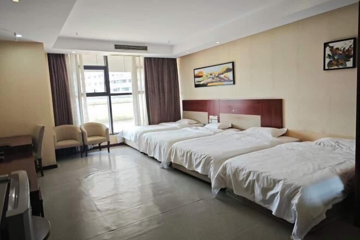 Ein Hotelzimmer mit zwei Betten, einem Schreibtisch, einem Stuhl und einem großen Fenster.