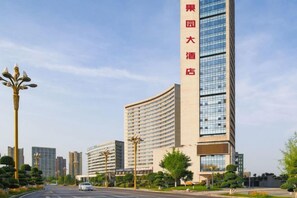 A high-rise hotel with a curved facade, multiple floors, and a prominent vertical sign. - Mujinhua Hotel (Chongqing)