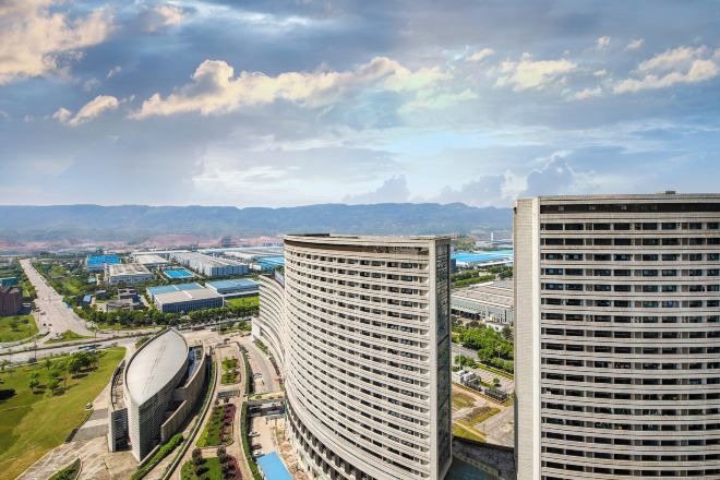A high-rise building with a curved facade, surrounded by other buildings and a clear sky.