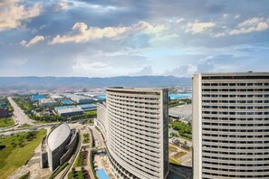 A high-rise building with a curved facade, surrounded by other buildings and a clear sky. - Mujinhua Hotel (Chongqing)
