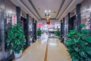 A corridor with potted plants, a chandelier, and a sign with Chinese characters. - Mujinhua Hotel (Chongqing)