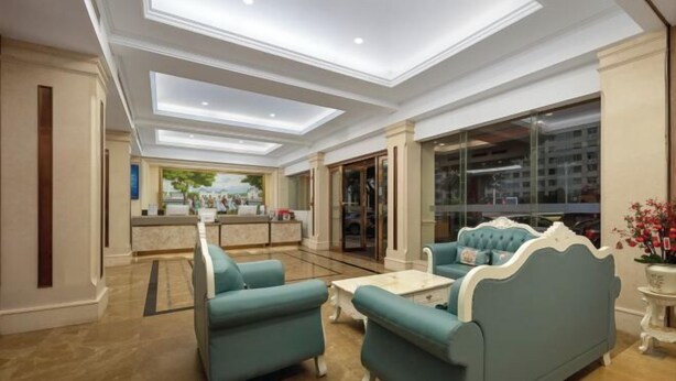 A spacious lobby with a reception desk, seating area with sofas, and a large window offering a view of the city. - Vienna Hotel Haikou International Trade City Friendship Sunshine City (Haikou)