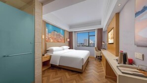 A hotel room with a bed, a desk, a window with a city view, and a painting on the wall. - Vienna Hotel Haikou International Trade City Friendship Sunshine City (Haikou)