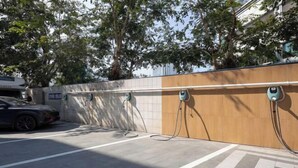 A parking area with electric vehicle charging stations, a car, and a building in the background. - Vienna Hotel Haikou International Trade City Friendship Sunshine City (Haikou)