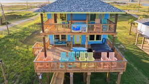 A two-story wooden house with a balcony, outdoor seating, and a sign advertising 'Sunshine Paradise'. - Surfside Beachfront Paradise (Surfside Beach)