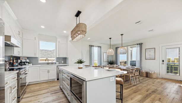 A modern kitchen with white cabinetry, a large island, stainless steel appliances, and pendant lighting. - Surfside Beachfront Paradise (Surfside Beach)