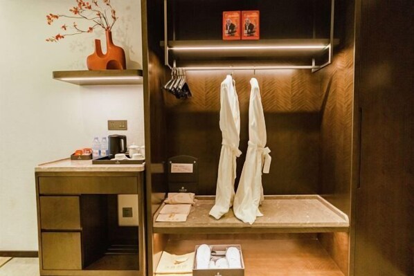 Une chambre d’hôtel avec une coiffeuse en bois, une étagère ornée d’objets décoratifs, un porte-serviettes et un meuble pour ranger les chaussures.