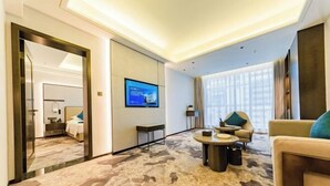 A hotel room with a large mirror, a television, a sofa, a coffee table, and a carpeted floor. - Bazhong Jiangbei Hotel (Bazhong)