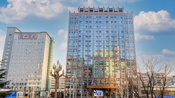 A multi-story building with a modern architectural design, featuring a prominent glass facade and a series of vertical lines at the top.