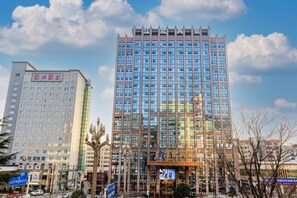 A multi-story building with a modern architectural design, featuring a prominent glass facade and a series of vertical lines at the top. - Bazhong Jiangbei Hotel (Bazhong)