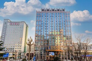 Un edificio de varios pisos con un diseño arquitectónico moderno, que cuenta con un llamativo frente de vidrio y una serie de líneas verticales en la parte superior.