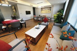 A modern living room with a sofa, a coffee table, and a dining area with chairs and a table.