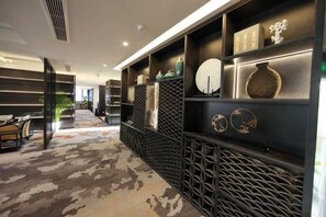 A hotel lobby with a patterned carpet, a reception desk, and a wall with decorative items. - Bazhong Jiangbei Hotel (Bazhong)