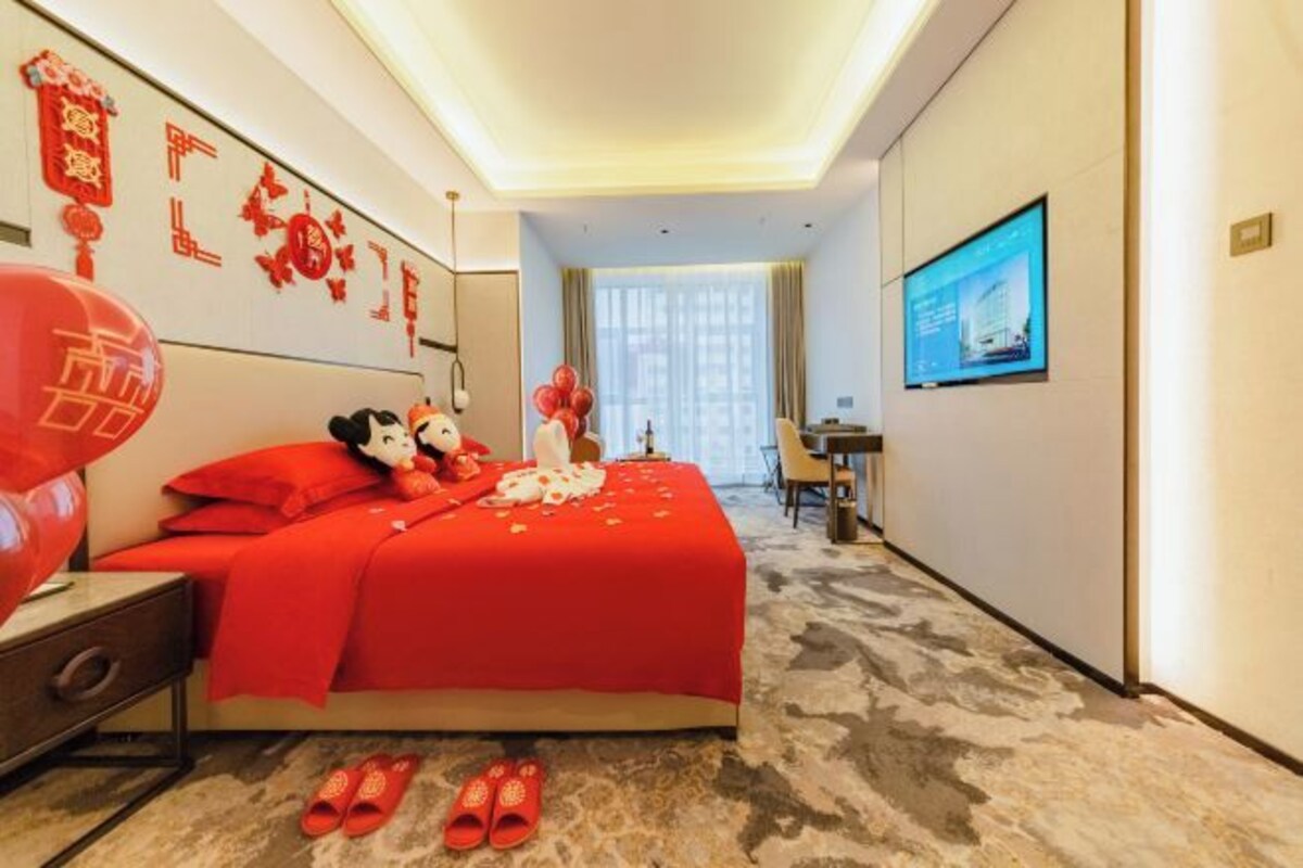 Une chambre d’hôtel avec un grand lit, un bureau, une télévision et une vue sur la ville.