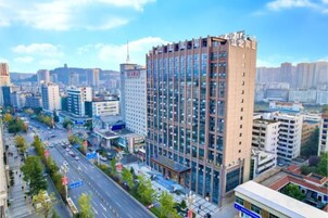 Un edificio de gran altura con varios pisos, rodeado de otros edificios y una calle concurrida.