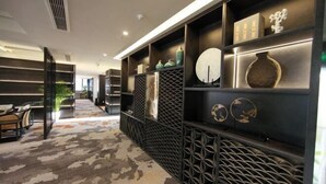 A modern hotel lobby with a patterned carpet, a reception desk, and a wall with decorative shelves. - Bazhong Jiangbei Hotel (Bazhong)