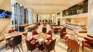 A spacious hotel dining area with multiple tables and chairs, a television mounted on the wall, and a decorative wall with plants. - Bazhong Jiangbei Hotel (Bazhong)
