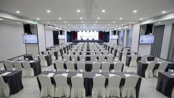 A conference room with rows of tables and chairs, equipped with projectors and screens.