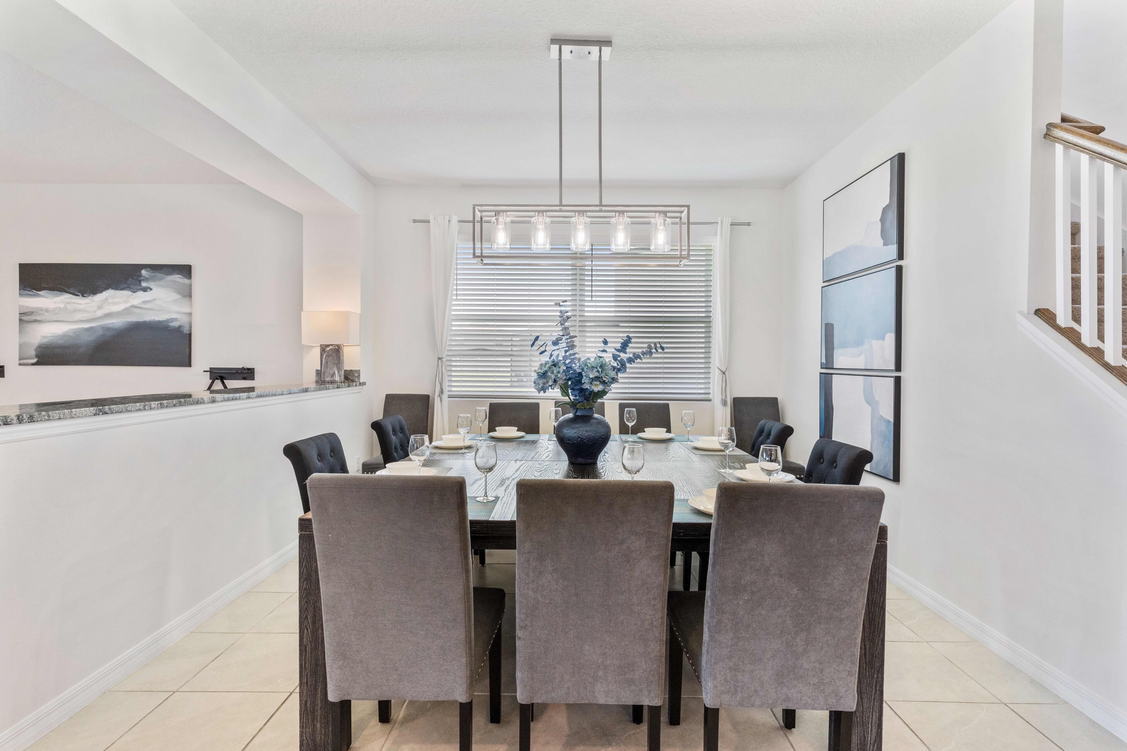 A dining area with a round table, six chairs, and a vase of flowers.
