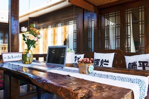 A traditional Japanese-style room with tatami flooring, a wooden desk with a laptop, a vase with flowers, and a bed with pillows. - Lijiang Ancient City Xishan Tea House Inn (Lijiang)