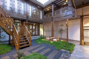 A traditional Japanese-style interior with a wooden staircase, tatami flooring, and a view of the outside.