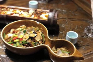 A ceramic dish with food, a small cup, and a teapot on a table.