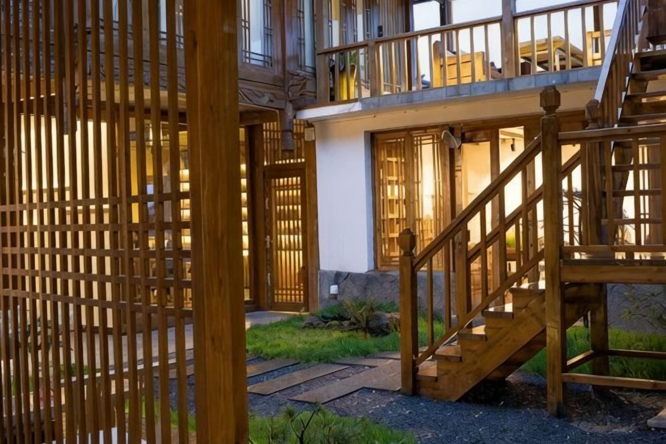 A wooden staircase leading to a building entrance, a wooden fence, and a well-maintained garden area.