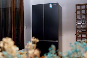 A black refrigerator in a room with a wooden cabinet and a glass door.