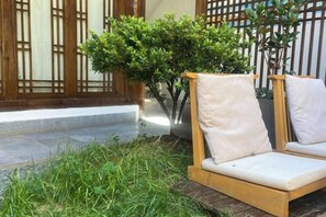 A wooden outdoor seating area with cushions, a potted plant, and a traditional wooden gate. - Lijiang Ancient City Xishan Tea House Inn (Lijiang)