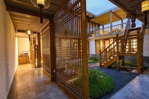 A traditional Japanese-style interior with a wooden sliding door, a staircase, and a small garden area.