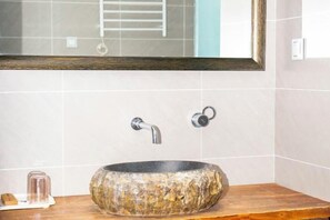 A bathroom with a round stone sink, two faucets, and a wooden countertop. - Lijiang Ancient City Xishan Tea House Inn (Lijiang)