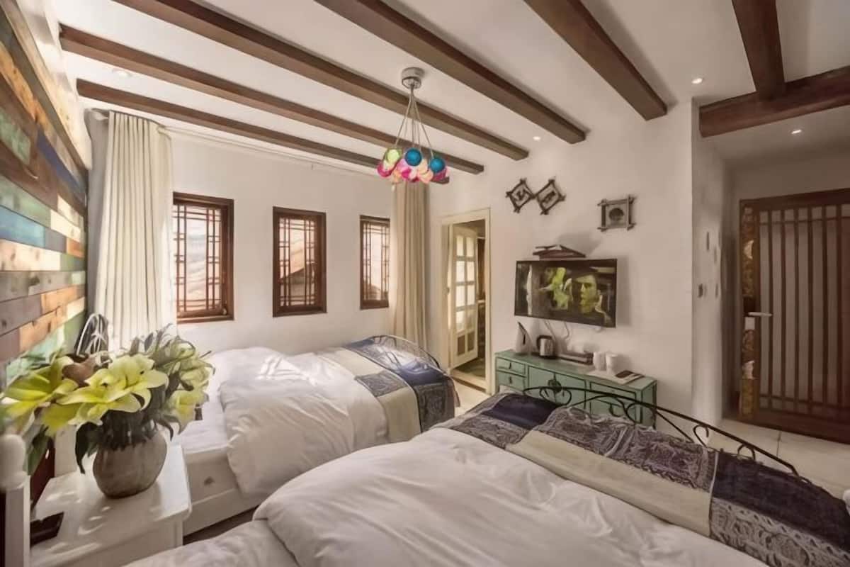 Une chambre avec deux lits, une commode, un miroir et une fenêtre avec des rideaux.