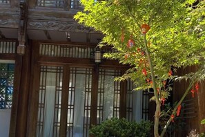 A traditional building with large windows and a tree with red flowers in front. - Lijiang Ancient City Xishan Tea House Inn (Lijiang)