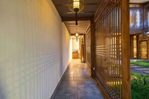 A corridor with a wooden fence, a tiled floor, and a hanging light fixture. - Lijiang Ancient City Xishan Tea House Inn (Lijiang)