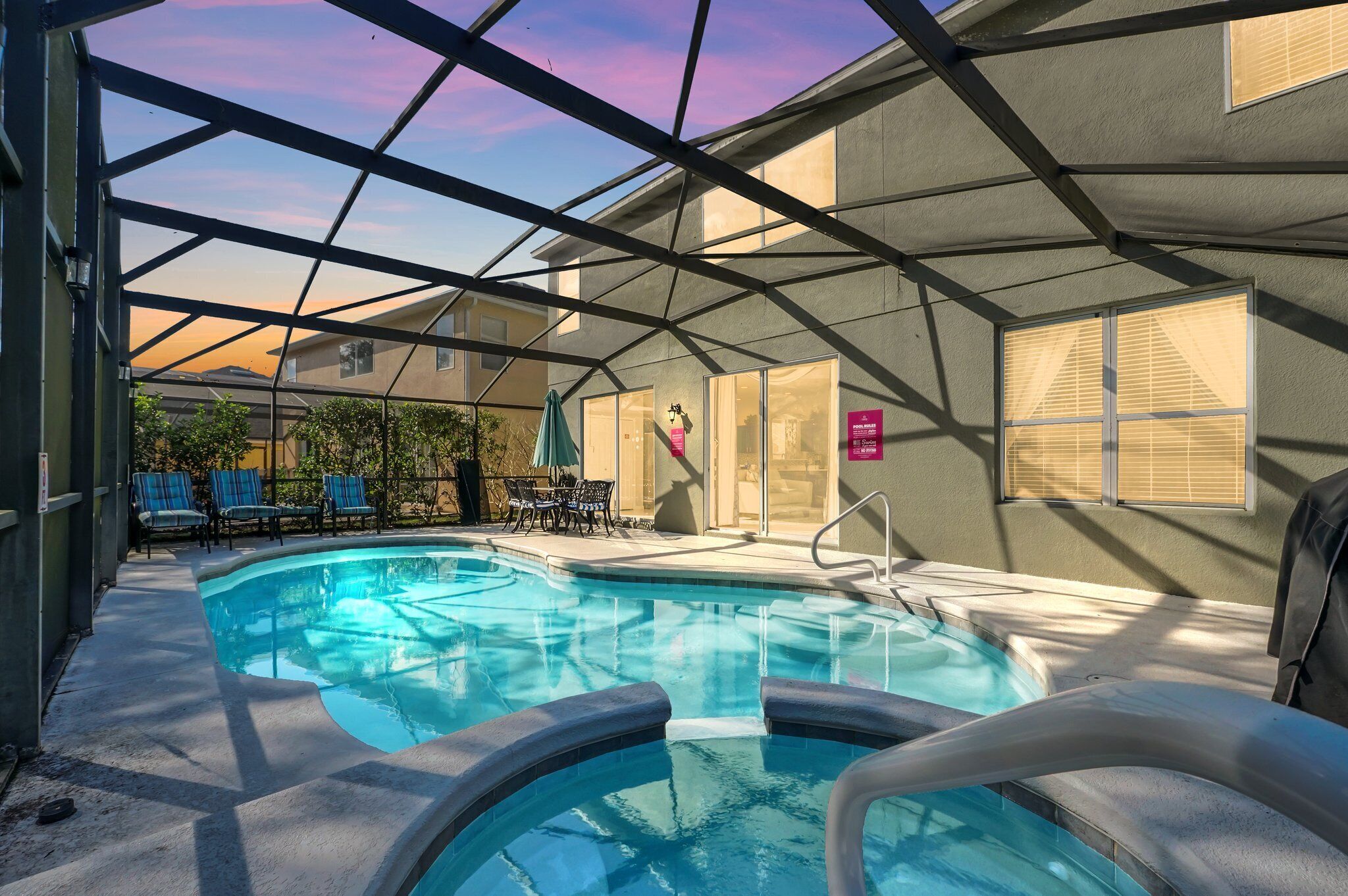 An indoor swimming pool with a glass ceiling, lounge chairs, and a hot tub.