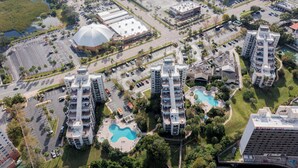 Un edificio residencial alto con varios balcones, una piscina y un estacionamiento.