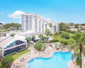 Un hôtel doté d’une piscine, un bâtiment moderne avec des balcons et un paysage verdoyant luxuriant.