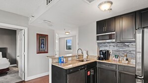Una cocina moderna con armarios oscuros, un refrigerador de acero inoxidable, un microondas y un lavavajillas.