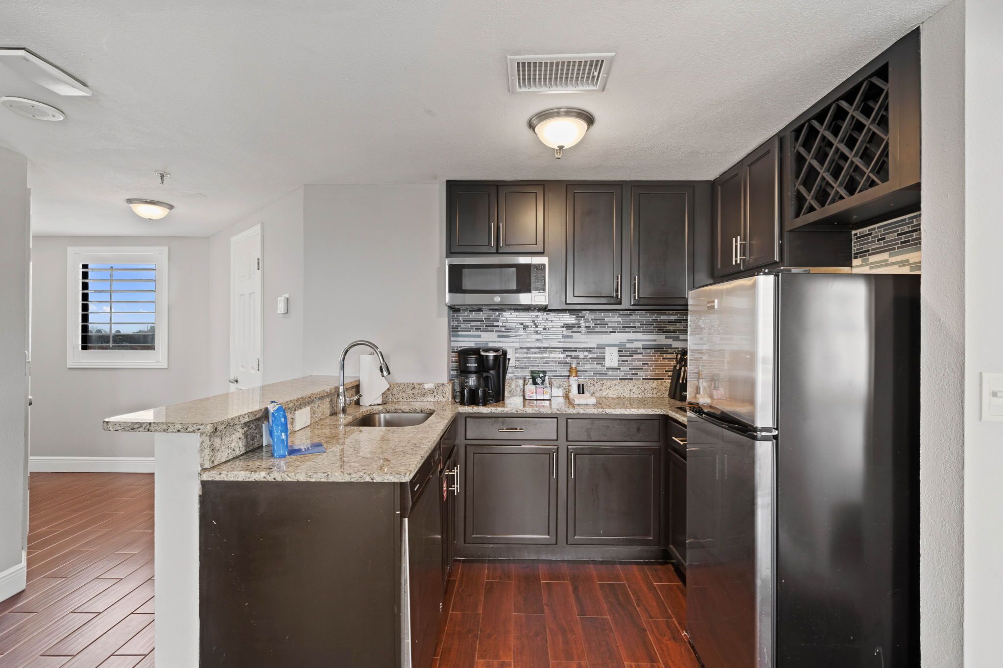 A modern kitchen with dark cabinets, stainless steel appliances, and a granite countertop.