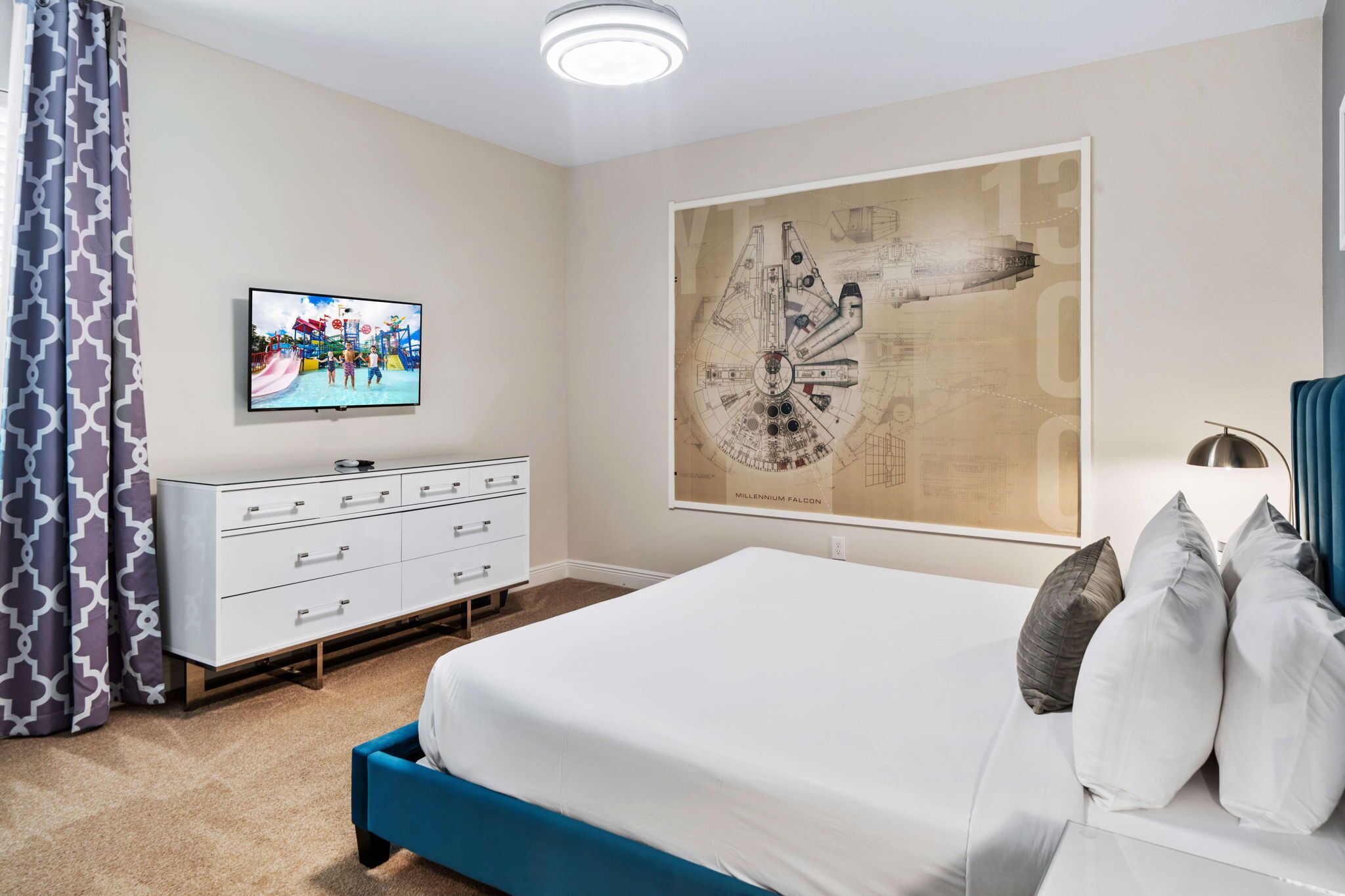 A bedroom with a bed, a dresser, a television, and a large wall art piece.