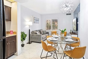 Uma zona de refeições moderna com mesa de vidro, cadeiras amarelas e um lustre.