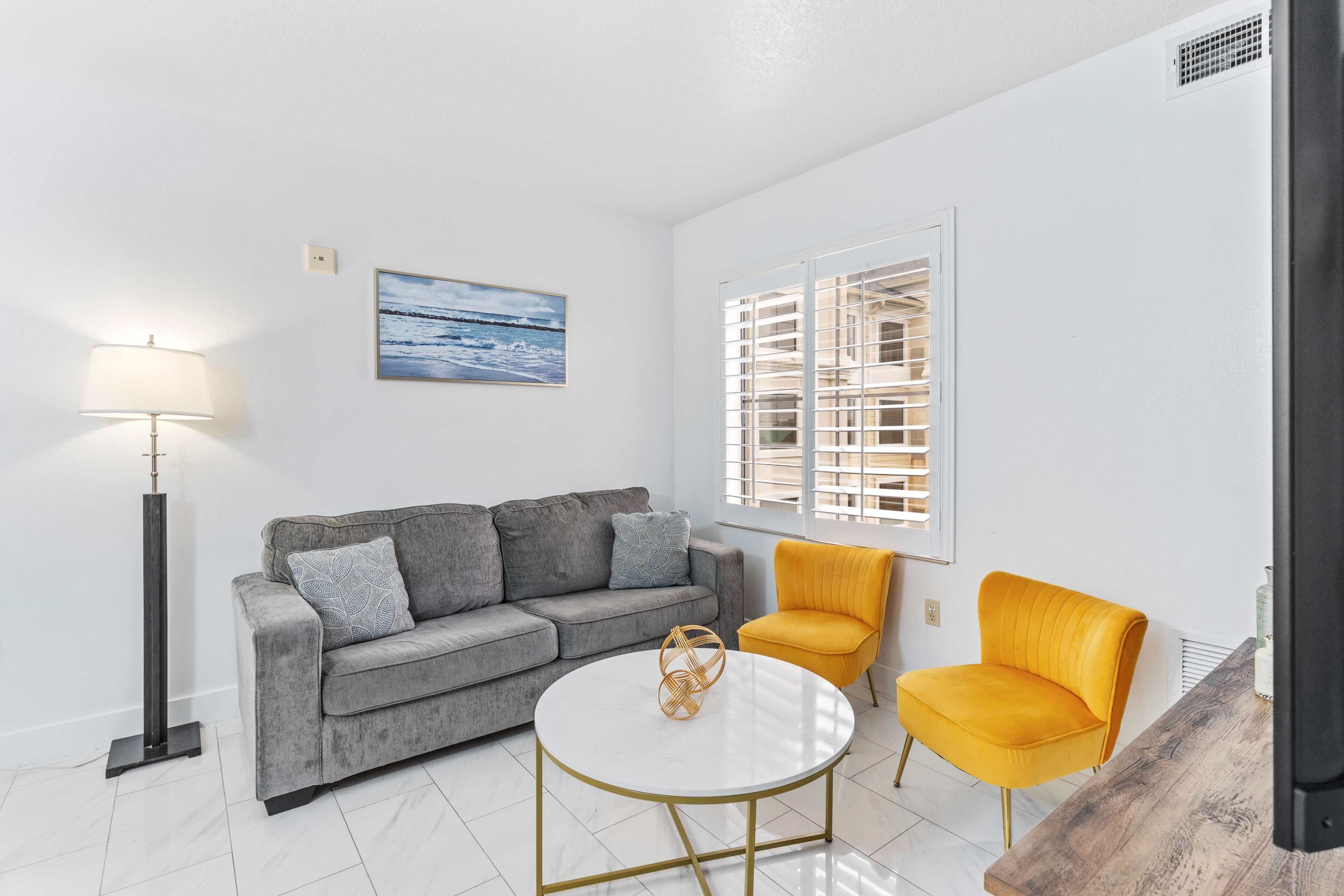 A modern living room with a grey sofa, a yellow armchair, a white coffee table, and a floor lamp.