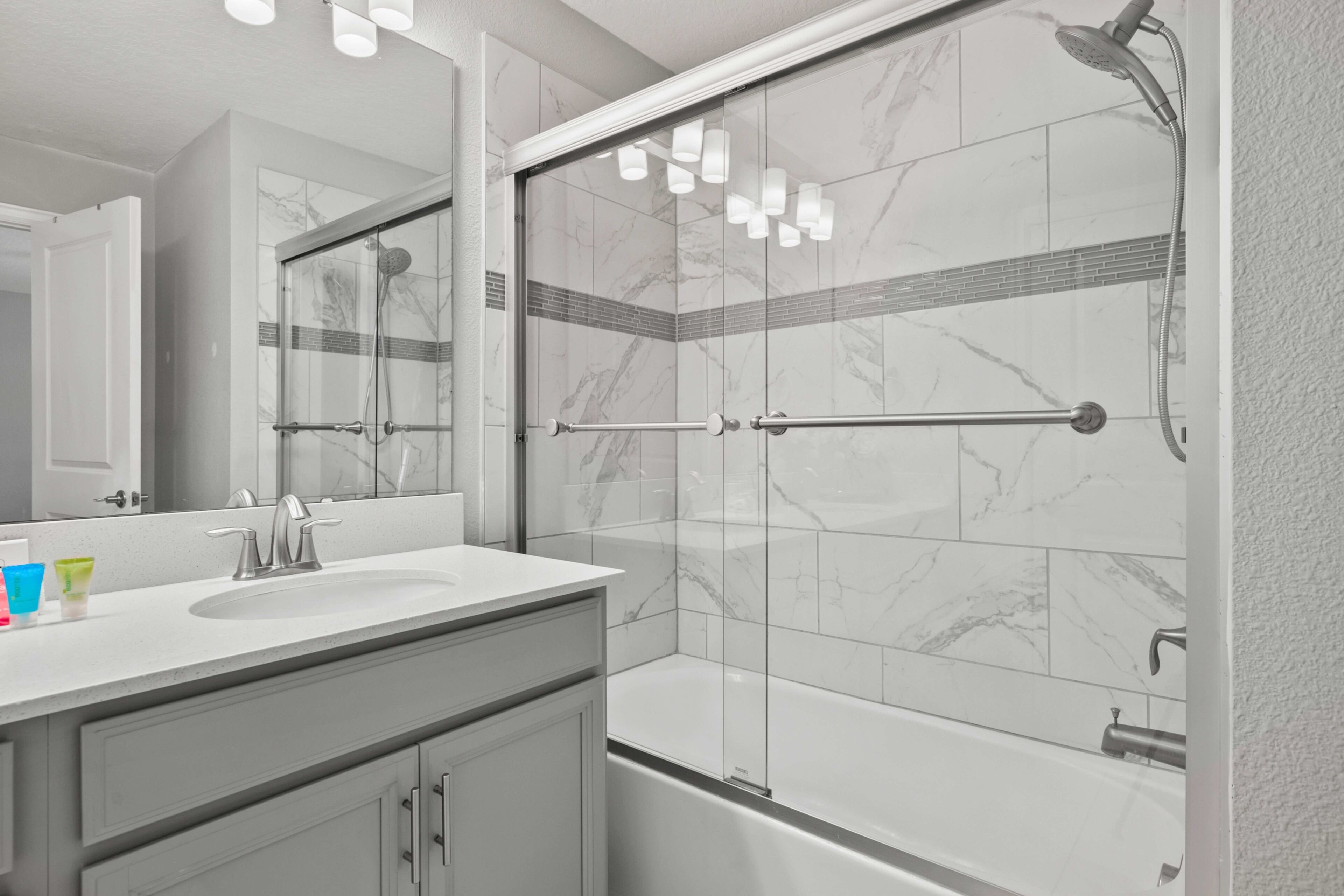 A modern bathroom with a glass-enclosed shower, a white sink, and a bathtub.