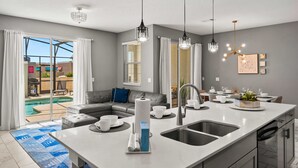 Une cuisine moderne dotée d’un grand îlot central, d’un coin repas et donnant sur une piscine.